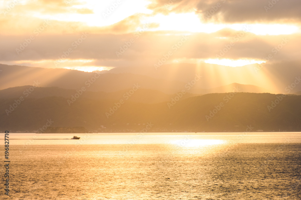 Stunning scene sunrise in the morning. Speed boat on the sea. Golden light go through the cloud to the mountain and sea.