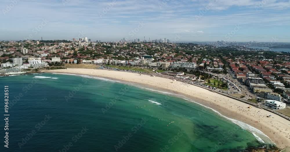 Magnificent panorama of Sydney Bondi beach waterfront and distant city CBD landmarks in aerial panning along sandy beach.
Magnificent panorama of Sydney Bondi beach waterfront and distant city CBD landmarks in aerial panning along sandy beach.