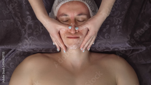 Close up of a handsome young man receiving facial massage at spa center