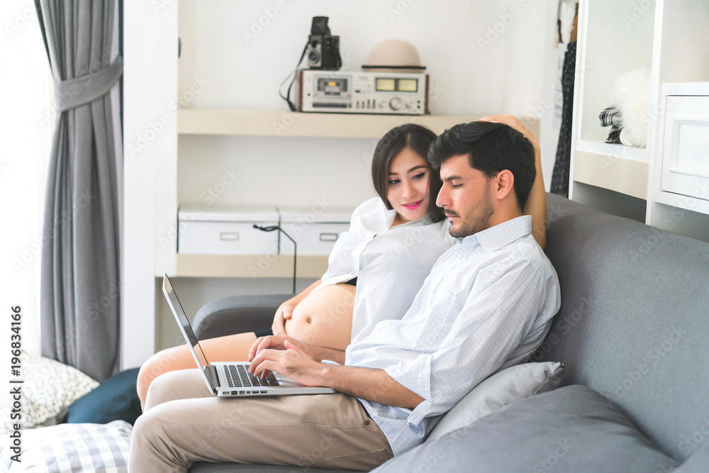 The pregnant woman encourages her husband who is working in the living room at home. The pregnant woman encourages her husband who is working in the living room at home.