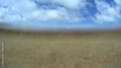 Underwater filming two girls playing with surfboard on sea water, water comes out from camera, sand beach island