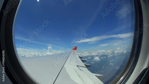 Air plane window view on wing and tropical island in ocean water, summer vacation
