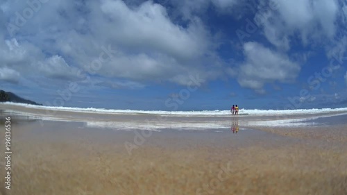 Girls with a surfboard coming into water, playing in splashing waves, summer vacation on island 