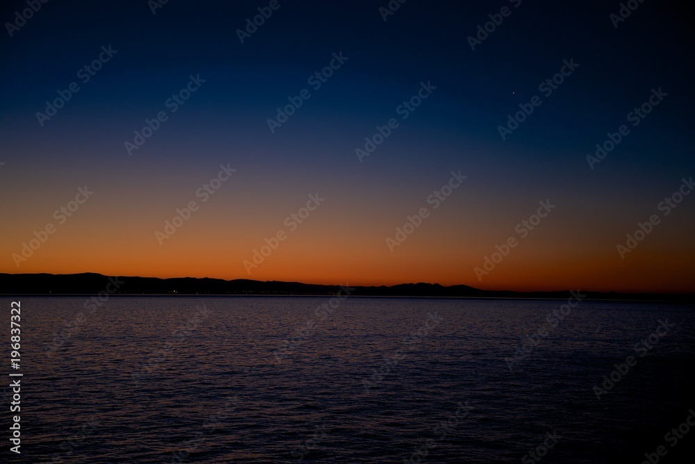 Colored sunset sky with beauty clouds and sun rays. Abstract seascape.