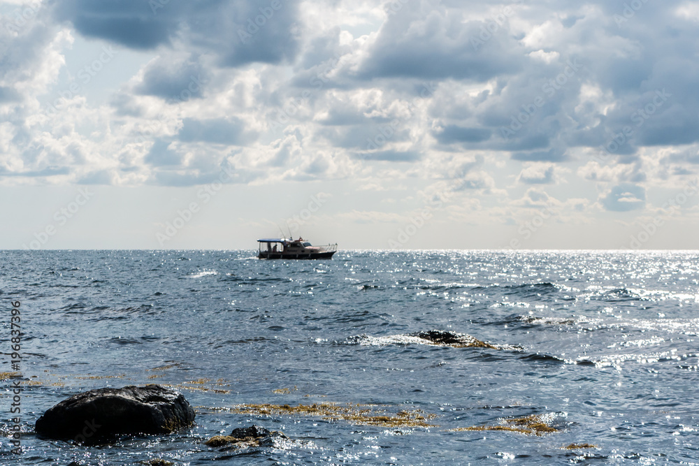 the rocky shore and fishing boat at sea