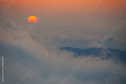 Sunrise on the Khambal mountane ridge in the clouds photo