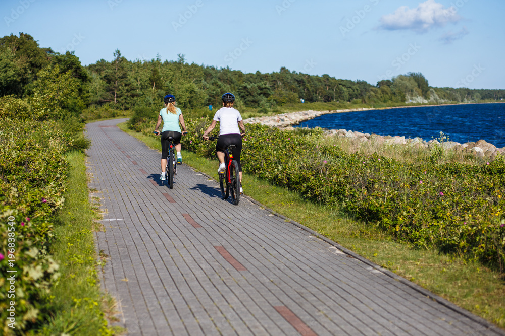 Obraz premium Women riding bicycles at seaside 