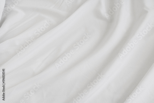 Crumpled of bedding sheet background. White fabric material surface.