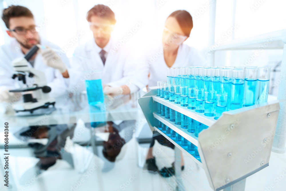 background image of scientists studying blue liquid in a flask background image of scientists studying blue liquid in a flask