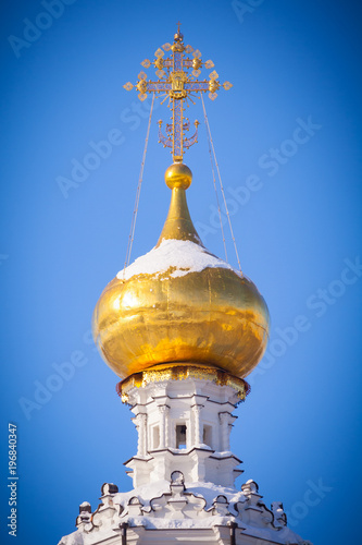 Gilded dome of a Christian white-stone temple a background of bright blue sky with vignette