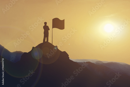 Silhouette of Businessman standing on mountain looking flag on hill at sunset. business target and success concept.