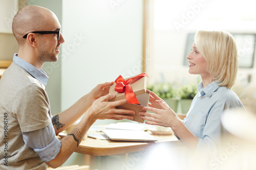 Young man congratulating his female colleague on holiday and showing her surprise in giftbox © pressmaster