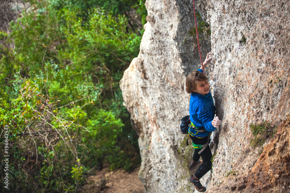 The boy climbs the rock.