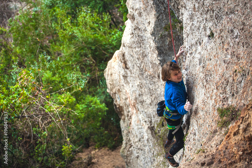 The boy climbs the rock.