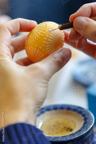 Hand einer Künstlerin beim gestalten von sorbischen Ostereiern mit Wachsbosiertechnik photo