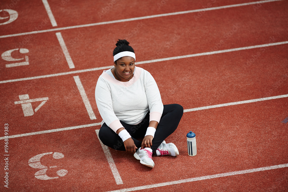 Cheerful and friendly female in sportswear having rest on race track