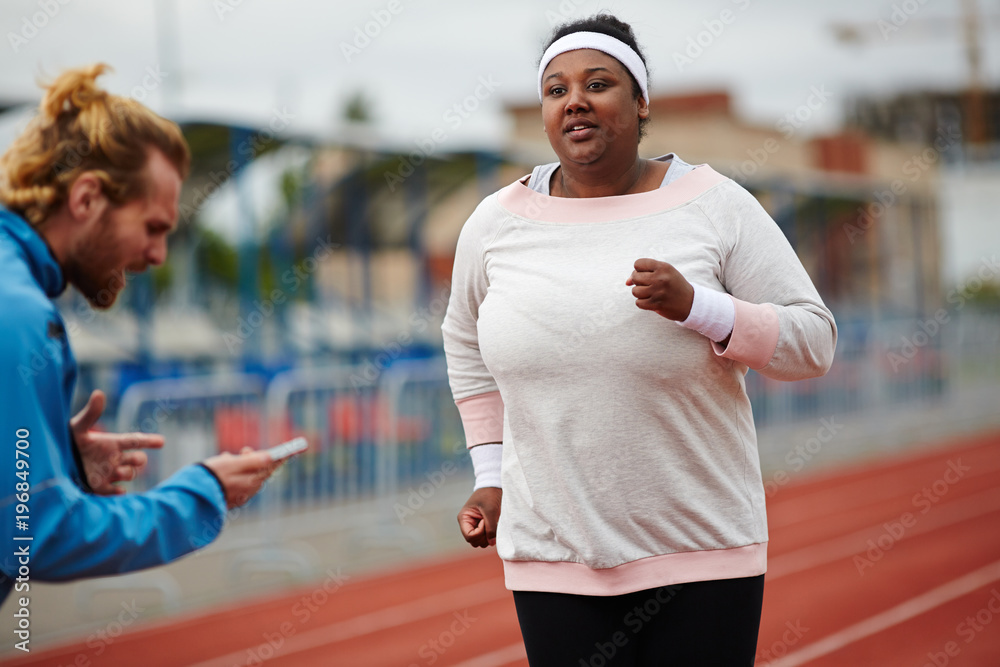 Trainer counting last seconds while young running woman getting closer to finish line Trainer counting last seconds while young running woman getting closer to finish line
