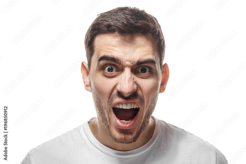 Closeup shot of furious shouting man standing isolated against white backgroung and screaming desperately. What have you done concept Closeup shot of furious shouting man standing isolated against white backgroung and screaming desperately. What have you done concept