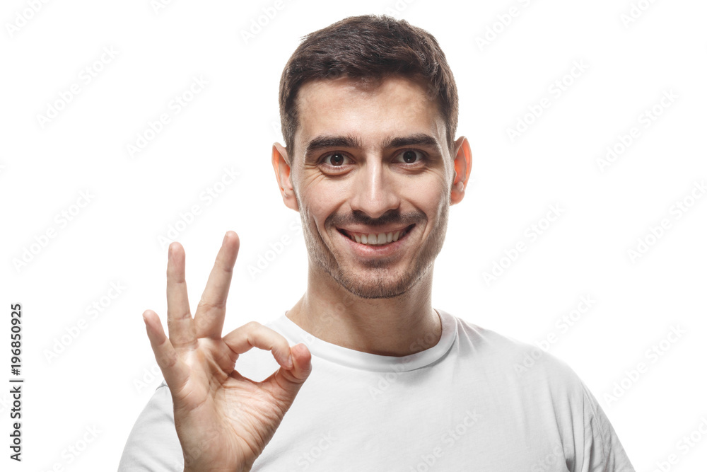 Young man in blank tshirt isolated on white background having happy look, smiling, gesturing, showing OK sign, OK-gesture with his fingers. Body language concept Young man in blank tshirt isolated on white background having happy look, smiling, gesturing, showing OK sign, OK-gesture with his fingers. Body language concept
