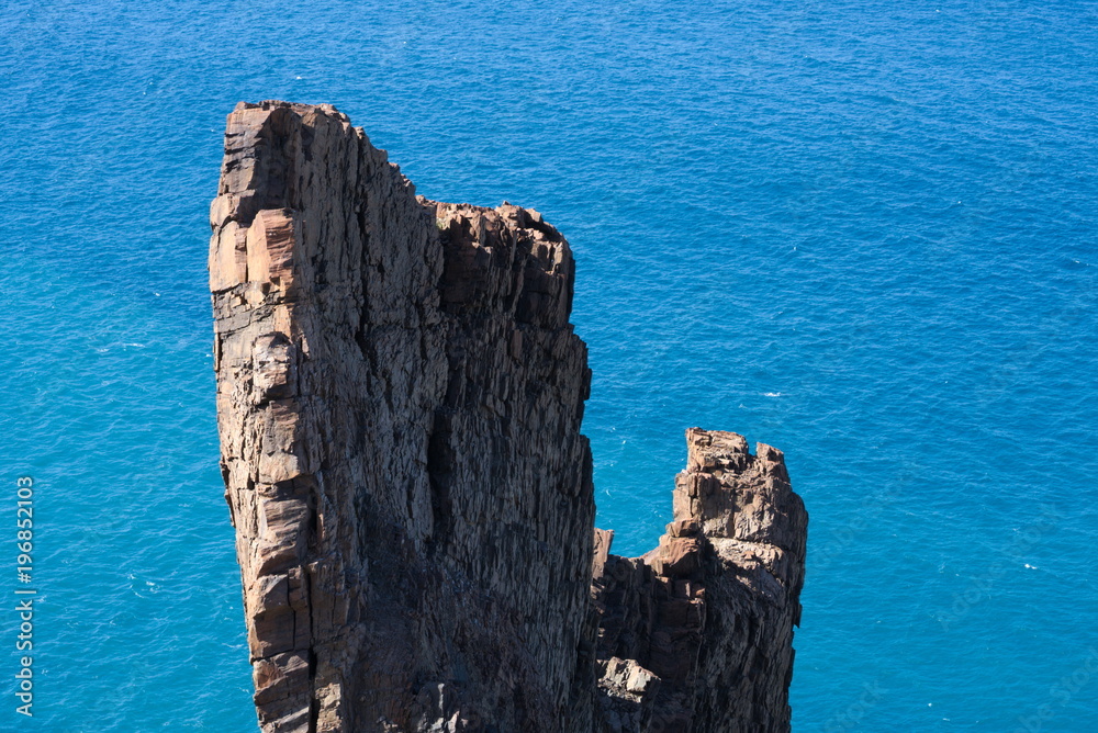 rock formation in front of the blue ocean