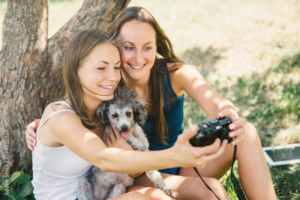 Happy young women hugging dog and looking in laptop. Relaxing in the park Happy young women hugging dog and looking in laptop. Relaxing in the park