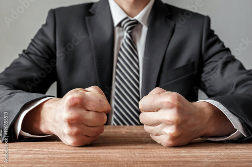 Valokuva Angry businessman with closed fists on the table.