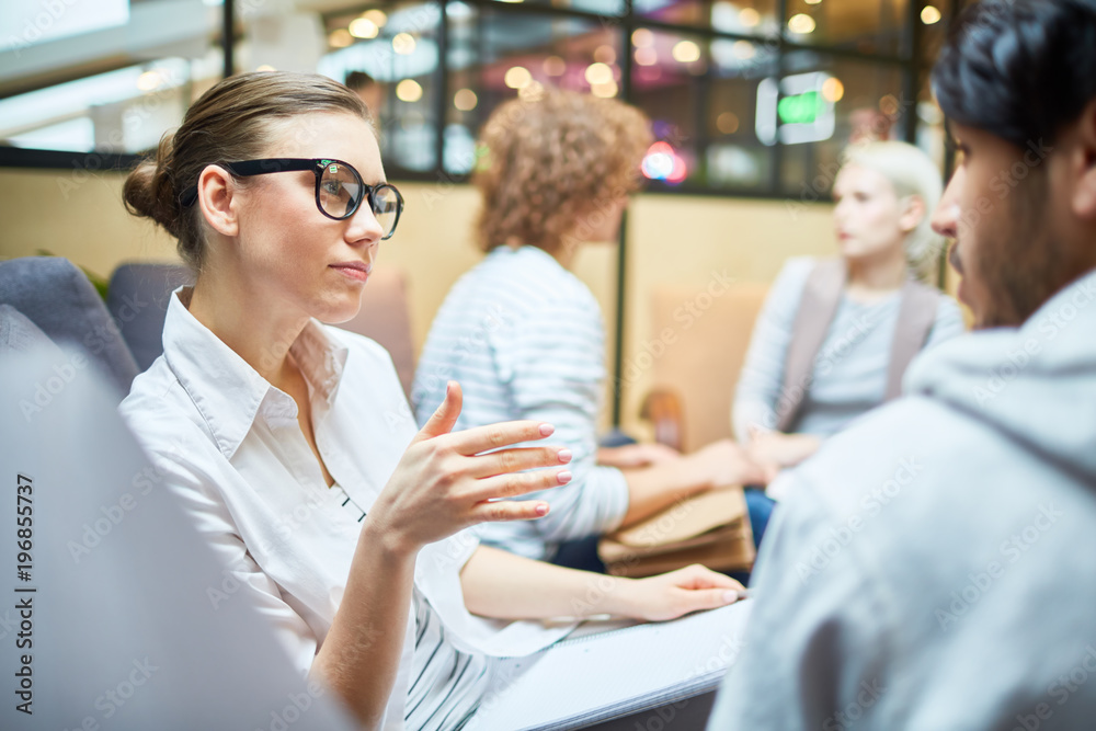 Obraz premium Pensive young woman explaining her point of view to one of co-workers during discussion of new design trends