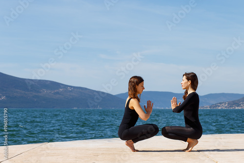 Two girls on the beach doing yoga on a pair, Montenegro