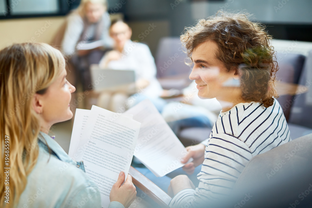 Fototapeta premium Two young financiers in casualwear consulting about details of contract at meeting