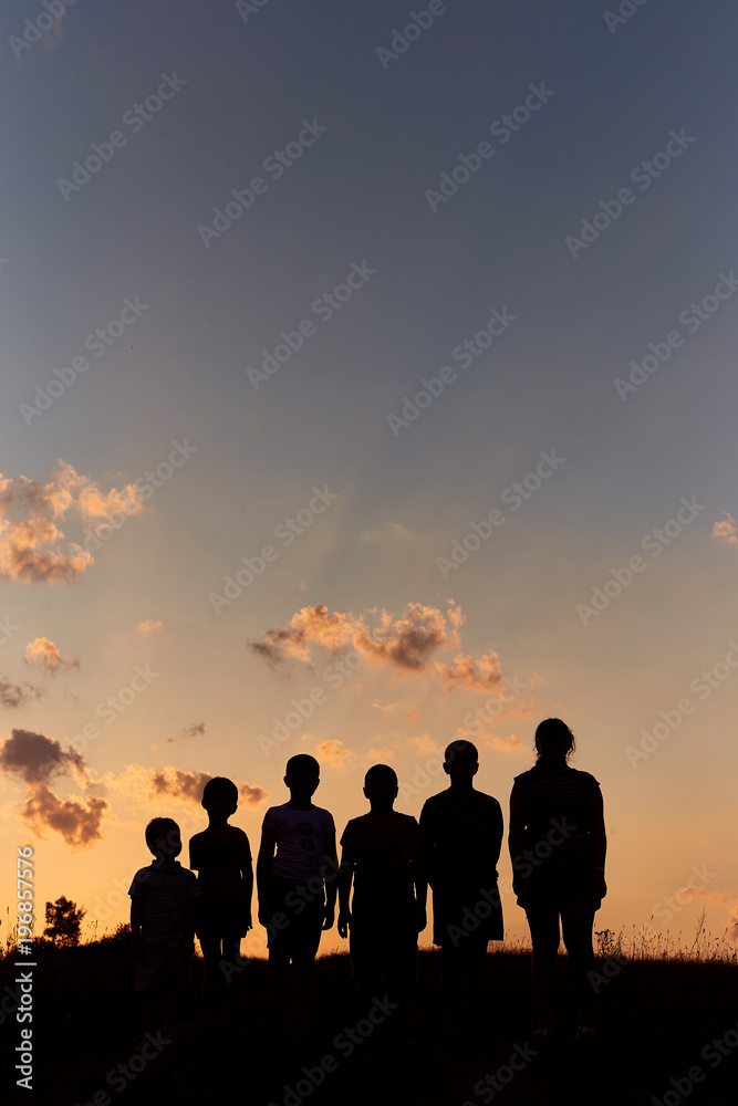 Six childrens stand on the field with sunset background sky