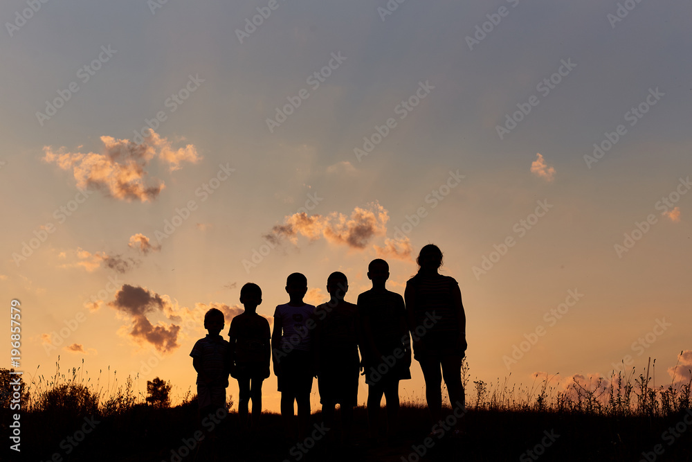 Six childrens stand on the field with sunset background sky