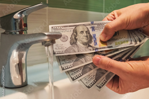 US dollars hung under running tap water photo