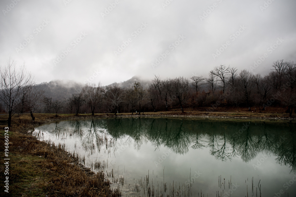 Fototapeta premium Landscape with misty morning fog in the Forest Lake or Beautiful forest lake in the morning at winter time. Azerbaijan nature.