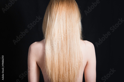 Back view of young girl with beautiful long blonde hair isolated on black