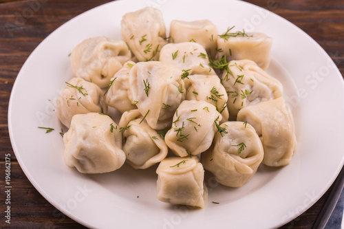 Pelmeni home-style with meat, are served with sour cream and greens