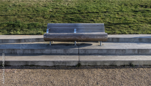 Modern bench in the park with space, near grass background and path, feeling peaceful, lonely and calm