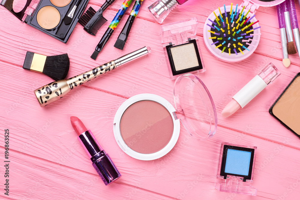 Cosmetics and tools on pink background. Blush powder, lipstick, eyeshadows and different cosmetics accessories. Feminine beauty background. Cosmetics and tools on pink background. Blush powder, lipstick, eyeshadows and different cosmetics accessories. Feminine beauty background.