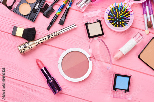 Cosmetics and tools on pink background. Blush powder, lipstick, eyeshadows and different cosmetics accessories. Feminine beauty background.