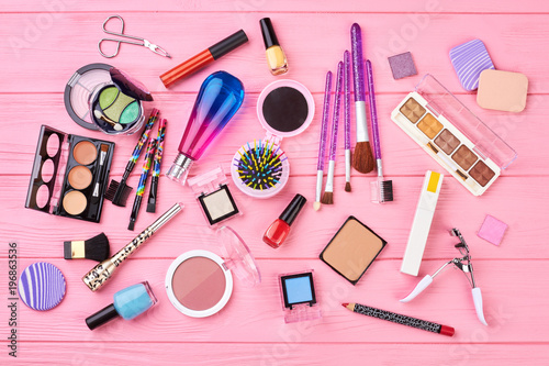 Flat lay decorative cosmetics, top view. Makeup tools and accessories on pink wooden background. Woman beauty table.