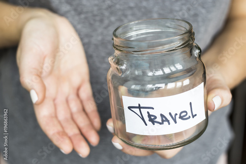 A woman is holding an empty piggy bank for travel. No money concept