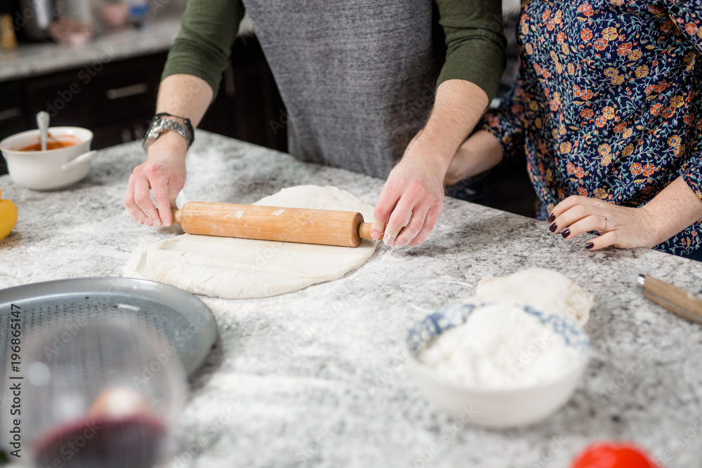 Couple Cooking Pizza Together in Kitchen, Rolling out dough, pizza dough, rolling pin Couple Cooking Pizza Together in Kitchen, Rolling out dough, pizza dough, rolling pin