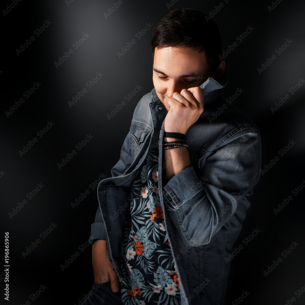Stylish guy in a denim jacket. Happy trendy young handsome guy in glasses and wearing a denim suit standing on a gray background, smiling. Portrait of a fashionable man in denim jacket Stylish guy in a denim jacket. Happy trendy young handsome guy in glasses and wearing a denim suit standing on a gray background, smiling. Portrait of a fashionable man in denim jacket