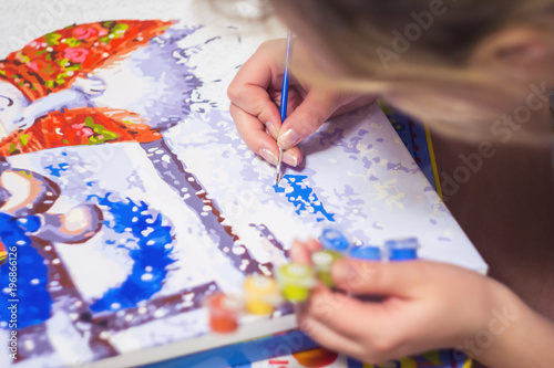 Woman is drawing the paint by numbers