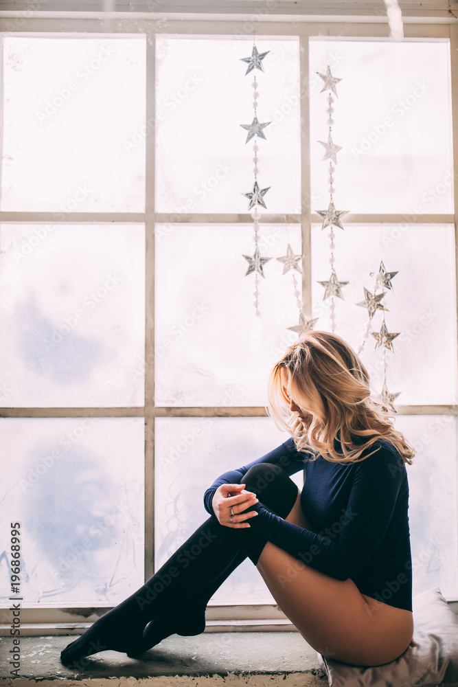 A young girl in a body by the window.