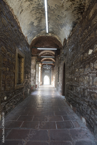 Old stone corridor with the door at the end
