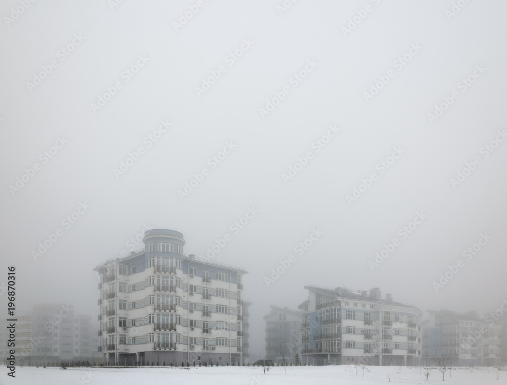 Fototapeta premium Mystical landscape of residential low-rise houses in dense fog