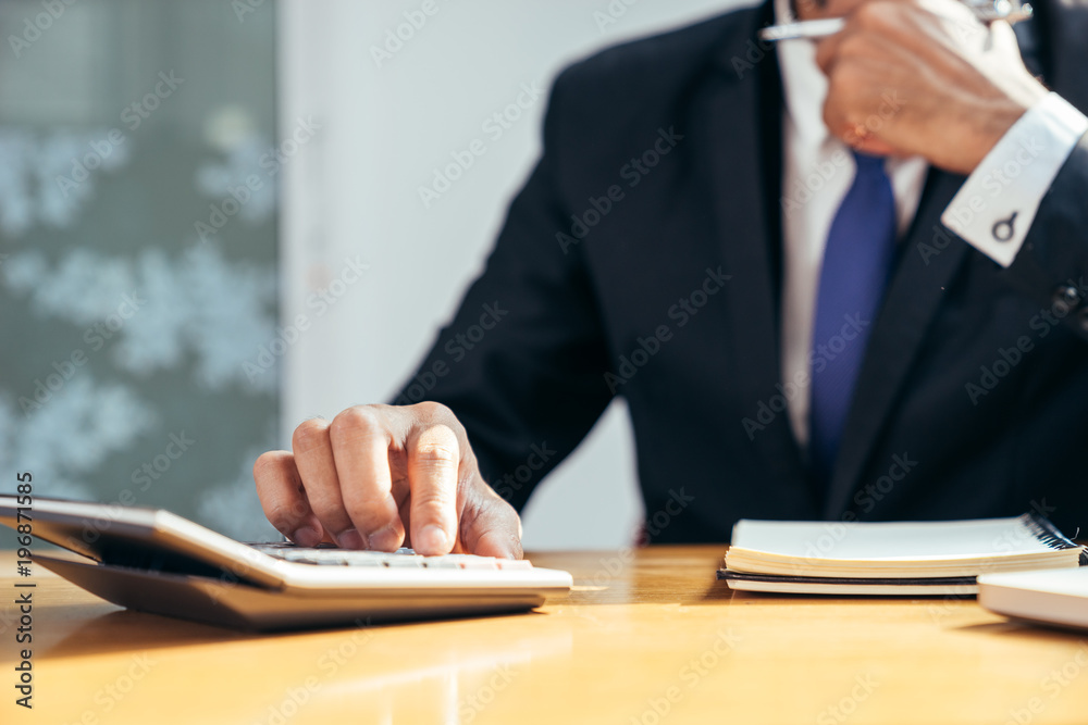 An asian businessman press the calculator button on his working desk by close-up his right hand, Business concept.