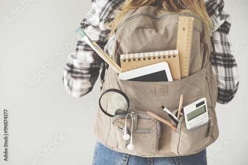 Student carrying backpack with stationery equipments