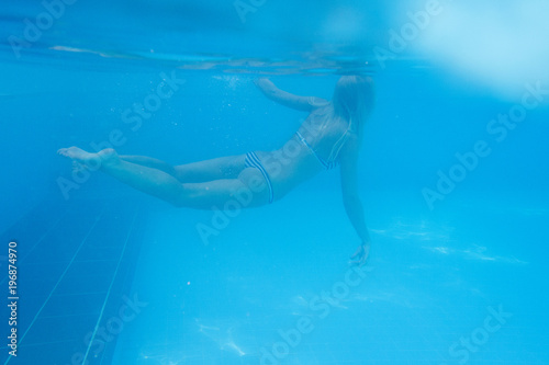 close-up shot of a woman swimming underwater in the pool.