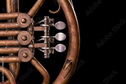 Vintage bronze pipes, valve, key mechanical elements french horn, black background. Good pattern, prompt music instrument. photo